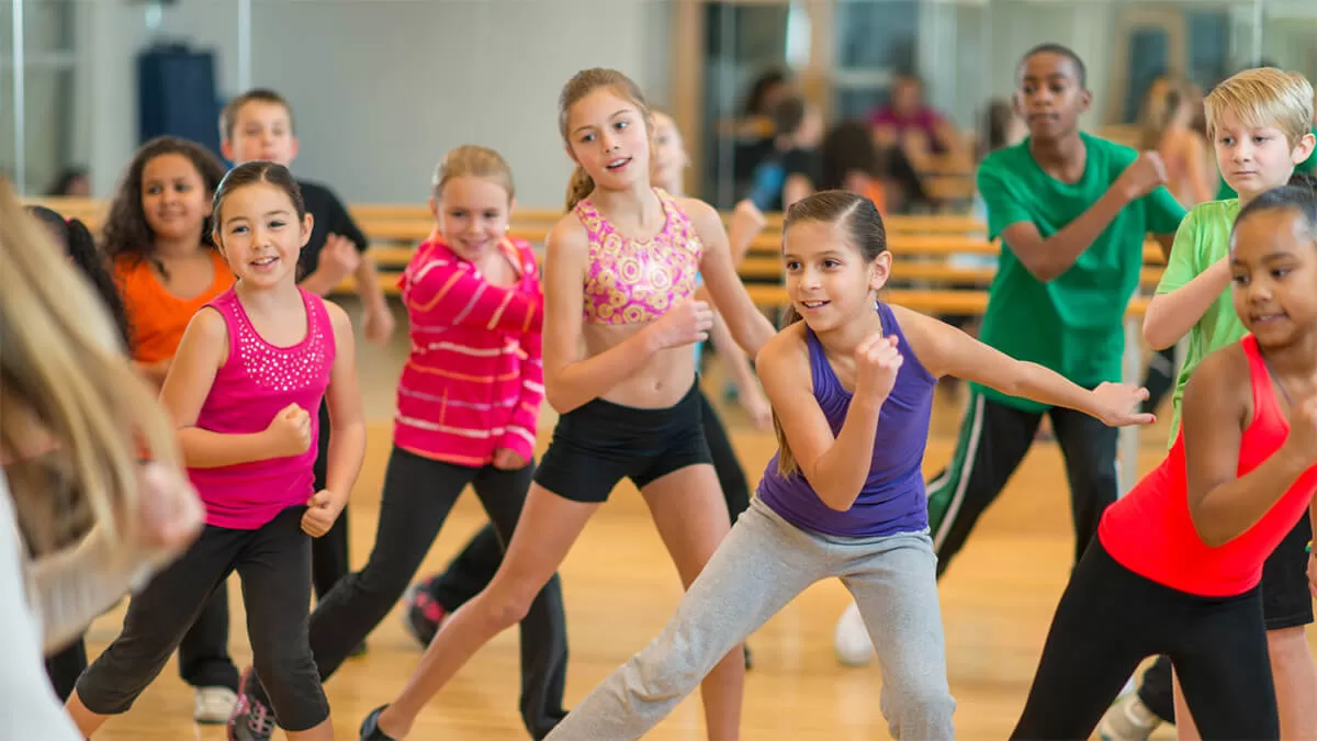 A group of children in dance poses, duing a dance class