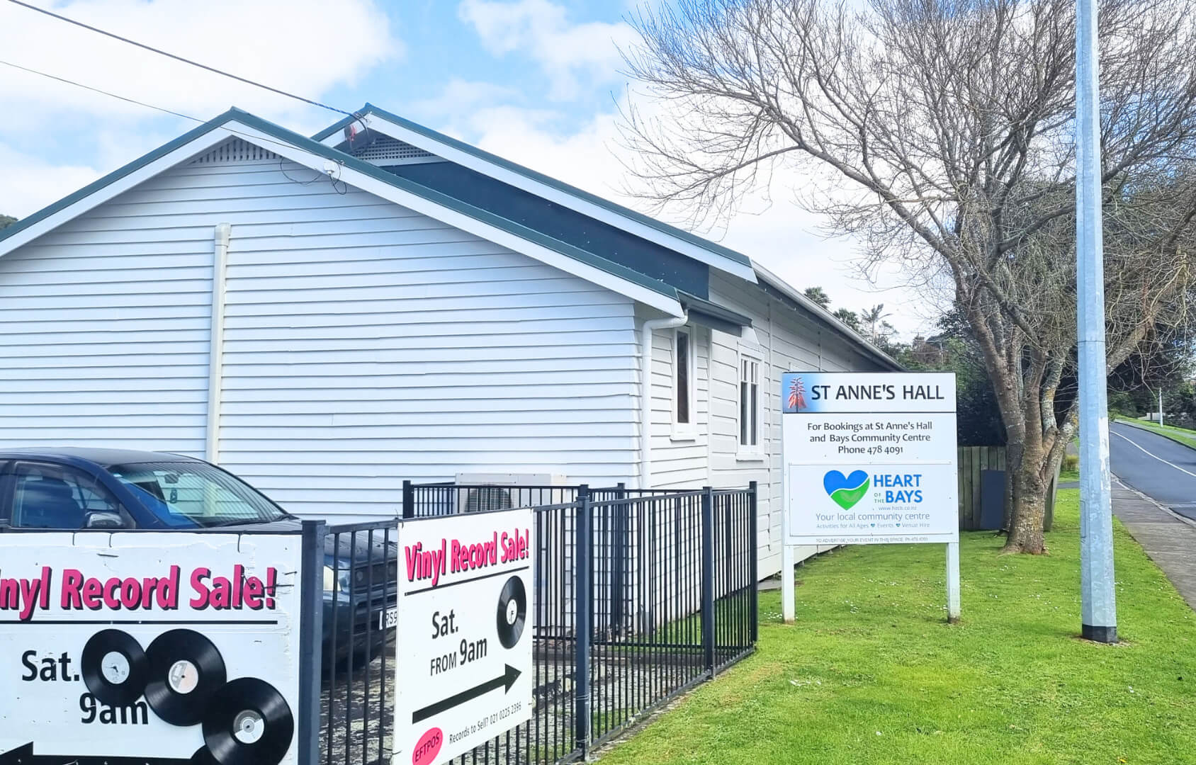 View of the exterior of the hall, showing fencing and signage